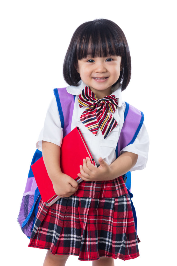 young girl in school uniform and holding a book