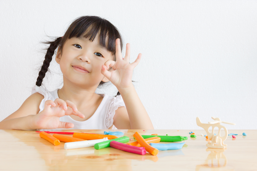 young girl playing with stick toys and a wooden helicopter