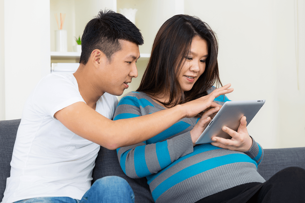 man and pregnant woman using ipad