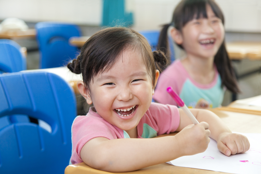 young happy girls drawing in class