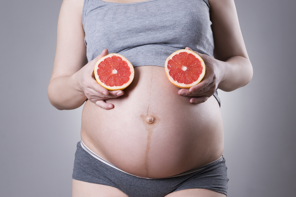 week 23 exposed pregnant belly with grapefruits