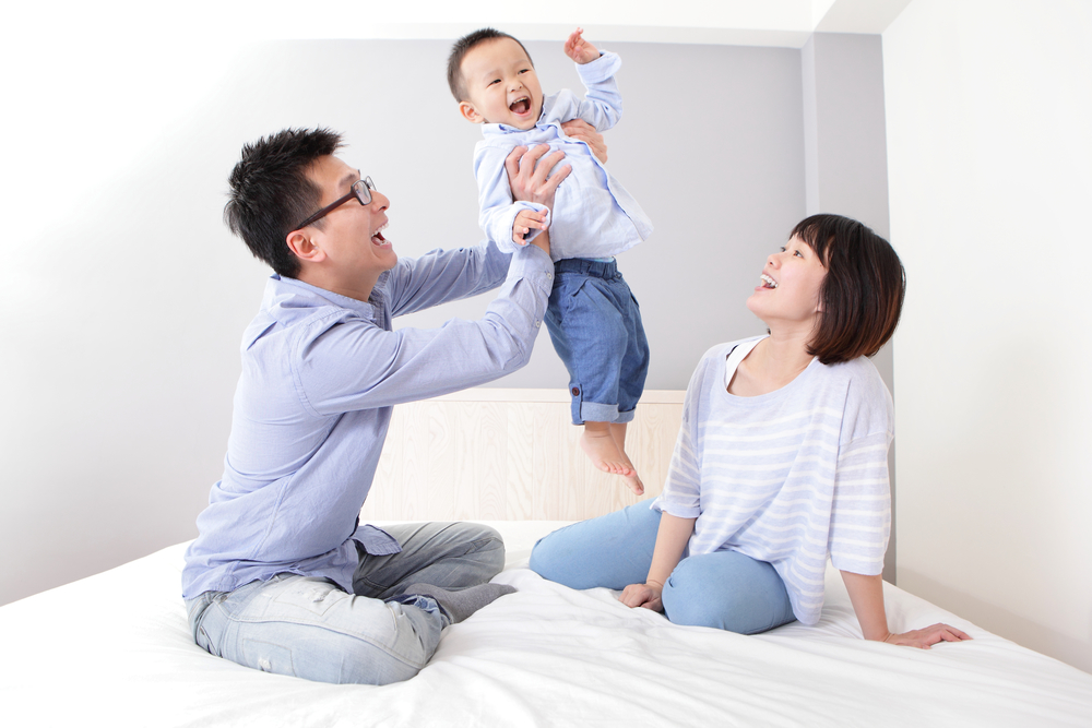 happy family father carrying toddler son and mother smiling