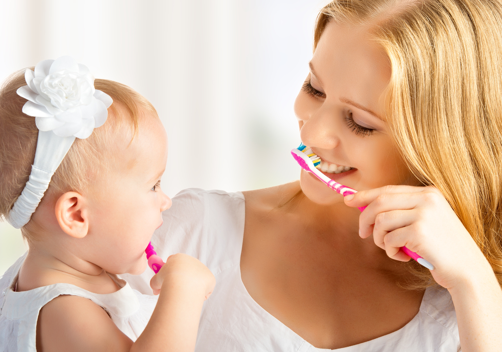 baby first teeth brushing with mother