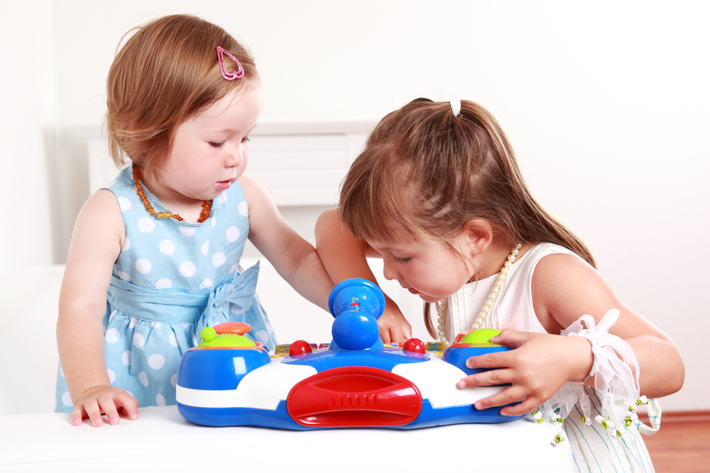 two preschool girls sharing a toy