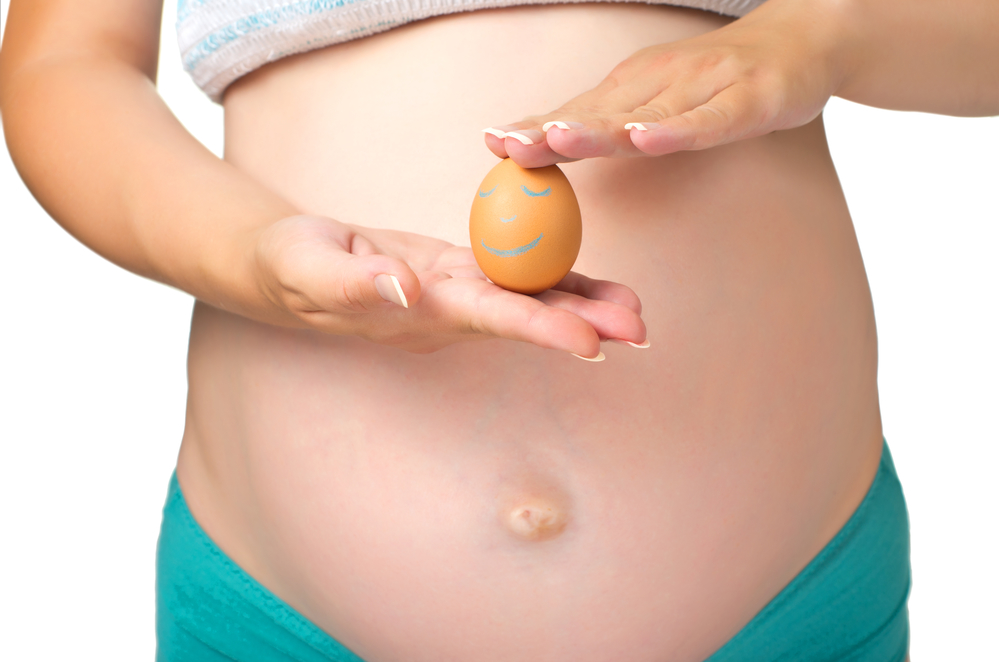 week 13 pregnant woman belly and chicken egg with smiley face