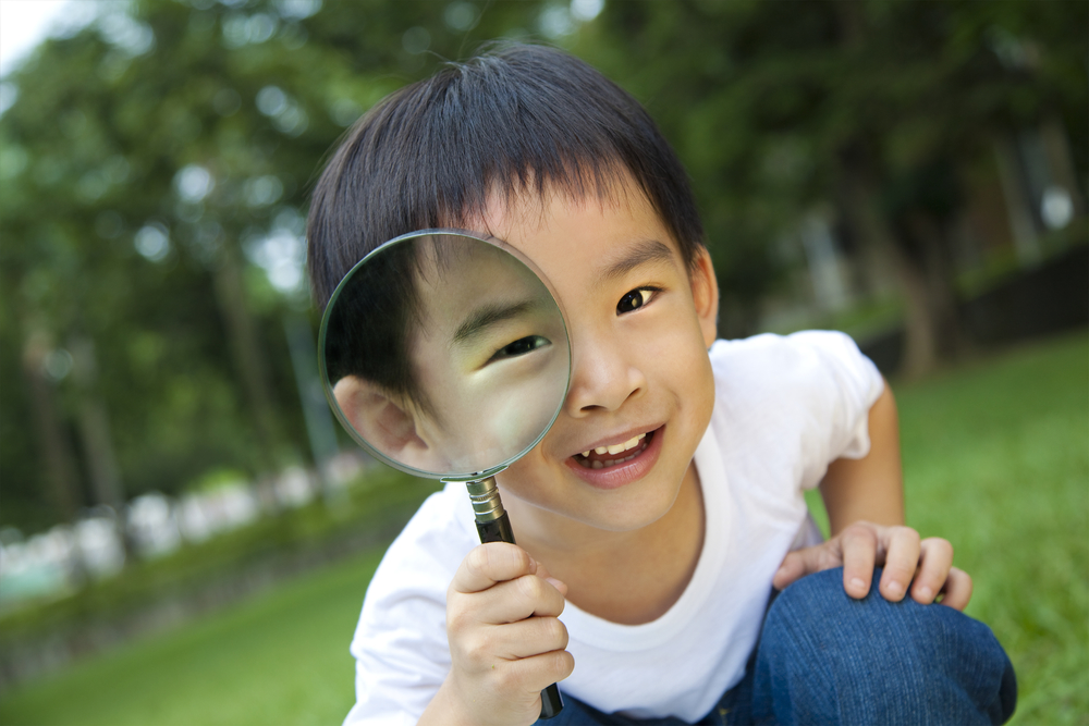 boy preschooler holding magnifying glass and smiling